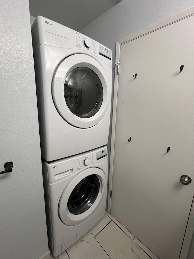 laundry room with light tile patterned floors and stacked washing maching and dryer