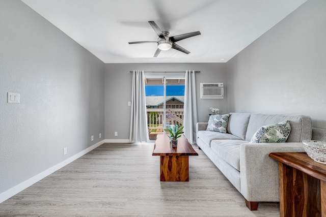 living room featuring light hardwood / wood-style floors, a wall unit AC, and ceiling fan