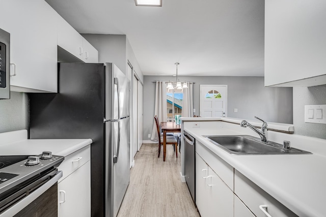 kitchen featuring pendant lighting, light hardwood / wood-style flooring, white cabinetry, appliances with stainless steel finishes, and an inviting chandelier