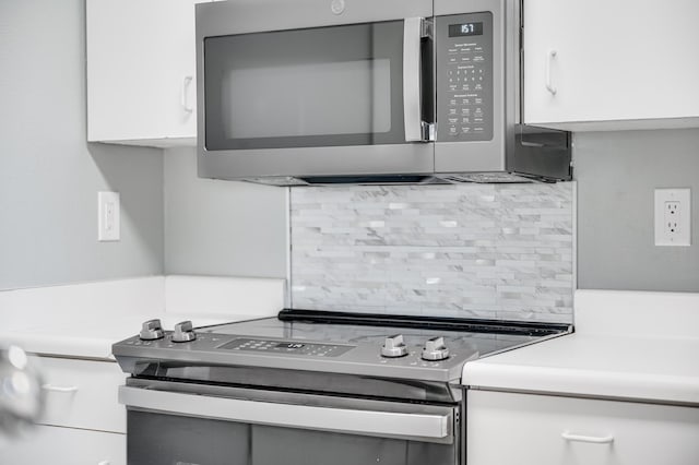 kitchen with white cabinets, stainless steel appliances, backsplash, and gray cabinetry