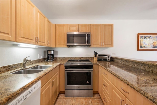 kitchen featuring stone counters, light brown cabinets, light tile patterned flooring, a sink, and appliances with stainless steel finishes