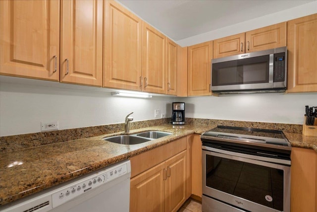 kitchen featuring stone countertops, light brown cabinetry, appliances with stainless steel finishes, and a sink