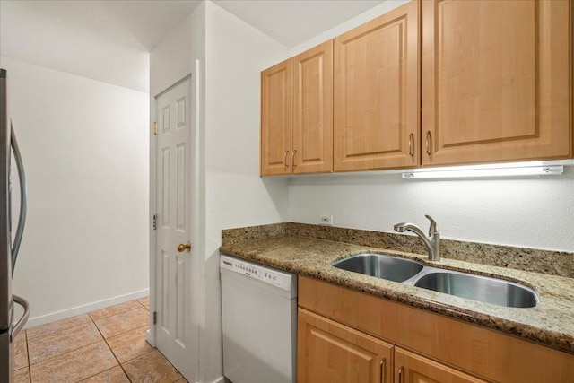 kitchen with freestanding refrigerator, dishwasher, light tile patterned floors, light stone counters, and a sink