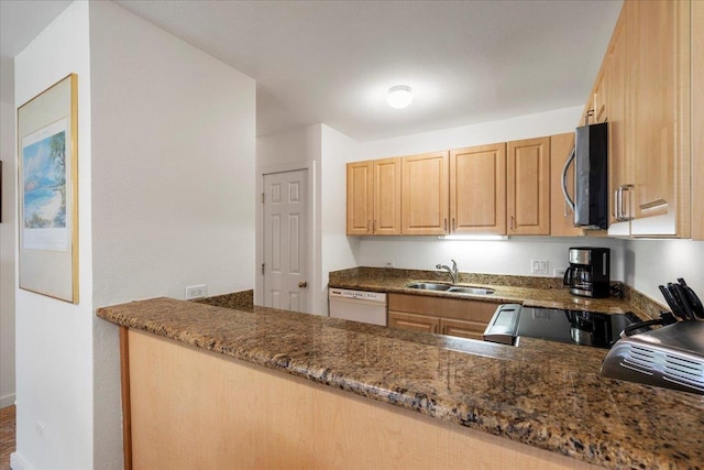 kitchen featuring a sink, stainless steel microwave, dark stone counters, light brown cabinetry, and white dishwasher