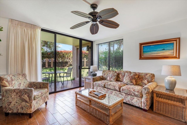 living room with expansive windows, plenty of natural light, wood finished floors, and a ceiling fan