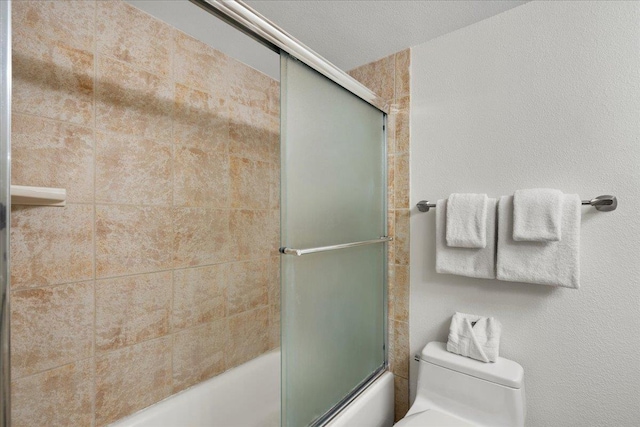 full bathroom featuring toilet and bath / shower combo with glass door
