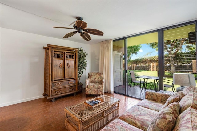 living area featuring expansive windows, dark wood-type flooring, baseboards, and a ceiling fan