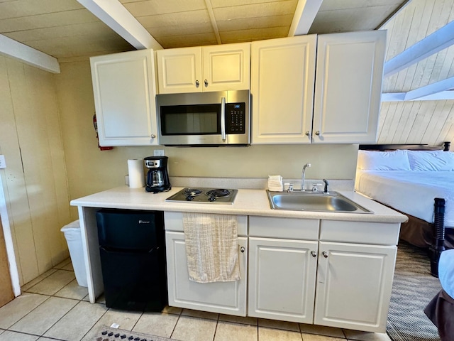 kitchen with sink, black electric cooktop, white cabinetry, and light tile patterned flooring