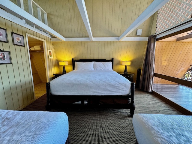 bedroom with wood walls, a closet, a spacious closet, and beamed ceiling