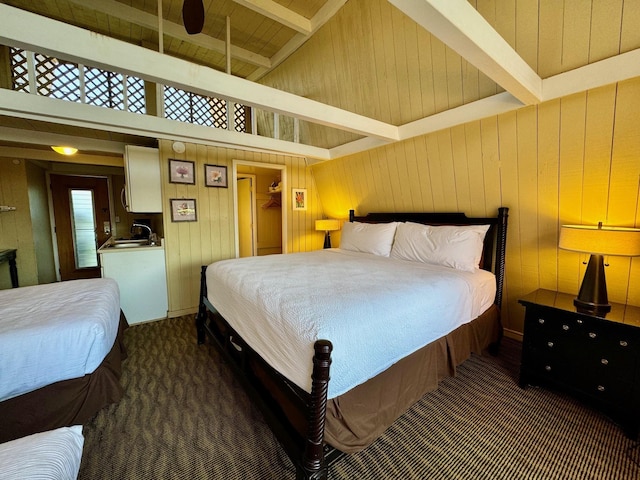 carpeted bedroom with sink, wooden ceiling, wooden walls, and lofted ceiling with beams