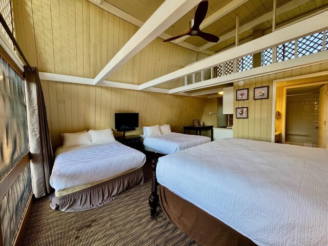 bedroom with wood walls, beamed ceiling, high vaulted ceiling, ceiling fan, and wooden ceiling