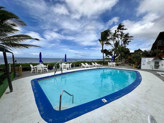 view of swimming pool with a patio and a water view