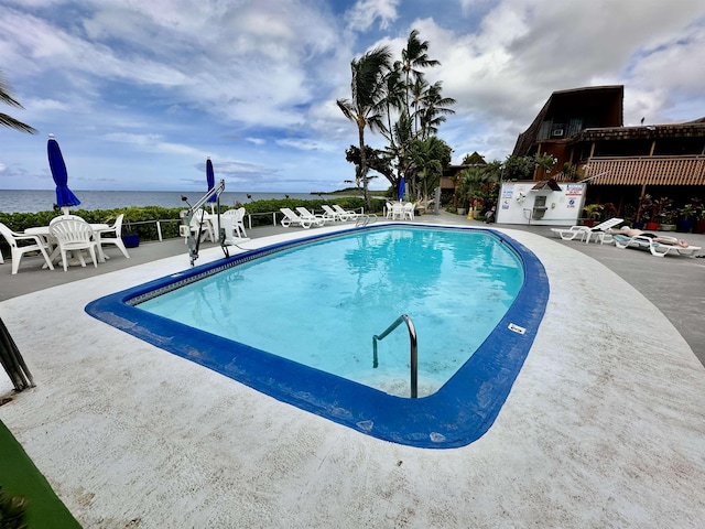 view of swimming pool with a patio and a water view