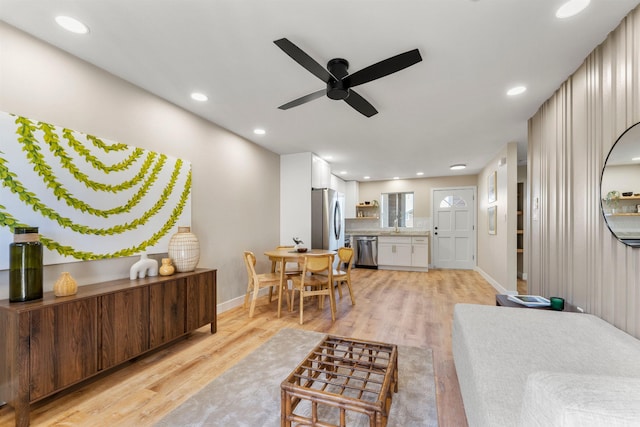 living room with light wood-type flooring, ceiling fan, and sink