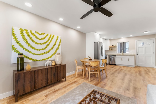 dining area with ceiling fan, light wood-type flooring, and sink