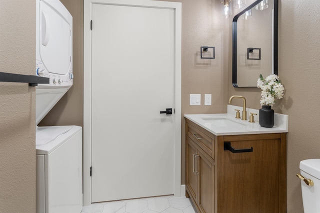 bathroom featuring vanity, stacked washer and clothes dryer, and toilet