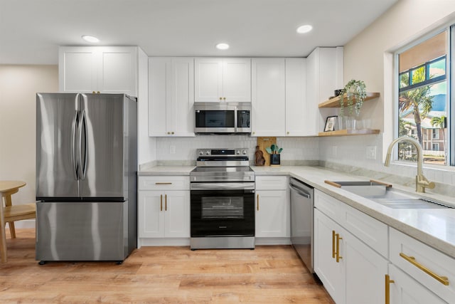 kitchen featuring a wealth of natural light, white cabinetry, sink, and appliances with stainless steel finishes