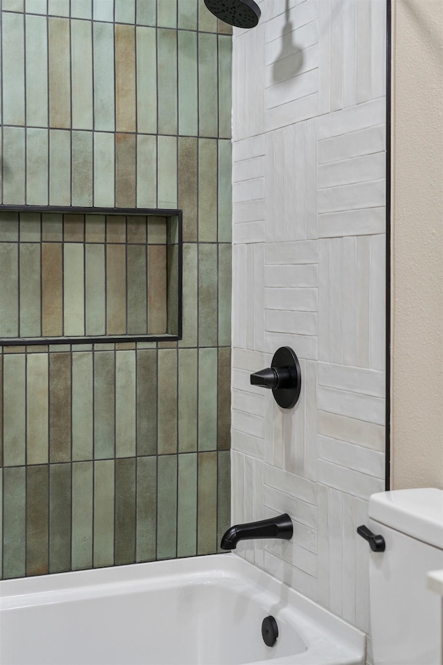 bathroom with toilet and tiled shower / bath