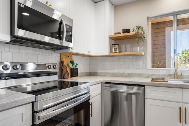 kitchen with light stone countertops, sink, decorative backsplash, white cabinets, and appliances with stainless steel finishes