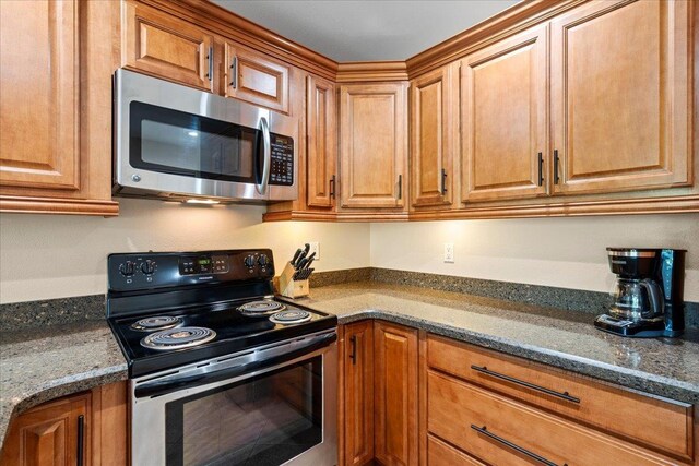 2777 S Kihei Rd Unit L-109, Kihei, HI 96753 - kitchen with appliances with stainless steel finishes, brown cabinetry, and dark stone countertops