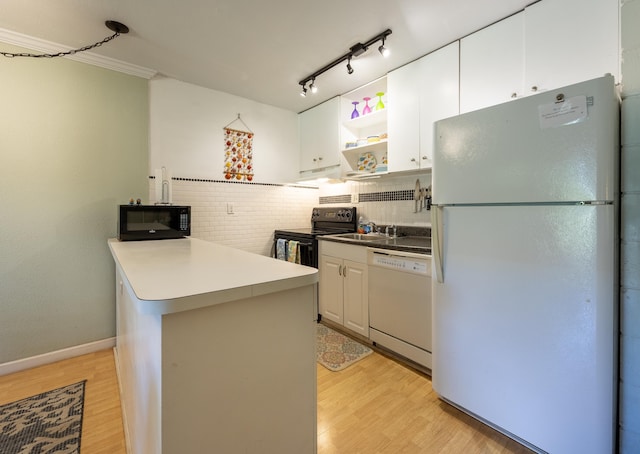 kitchen with kitchen peninsula, sink, light wood-type flooring, white cabinets, and black appliances