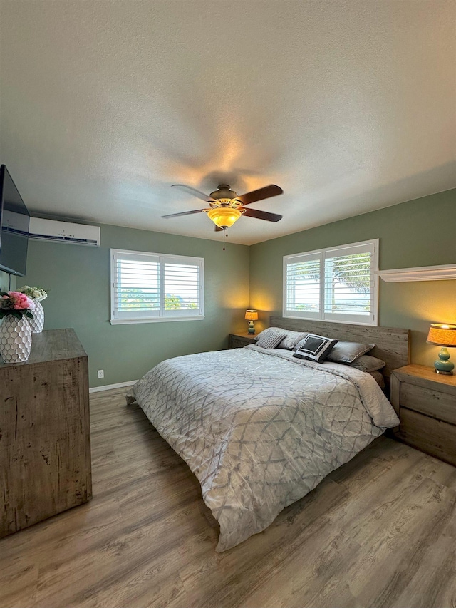 bedroom featuring multiple windows, ceiling fan, hardwood / wood-style floors, and a textured ceiling