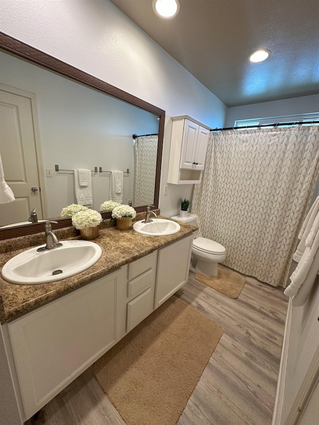 bathroom featuring hardwood / wood-style floors, vanity, toilet, and curtained shower