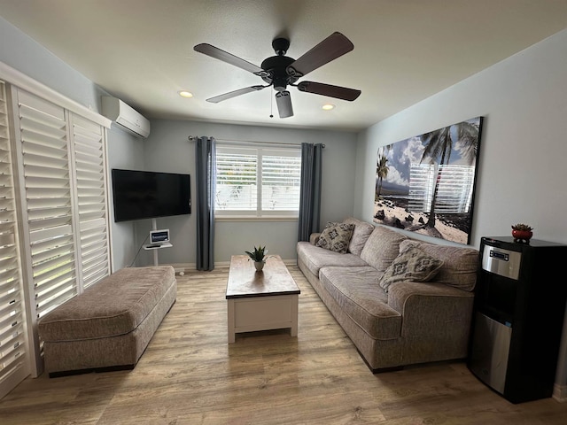 living room featuring ceiling fan, an AC wall unit, and light hardwood / wood-style flooring