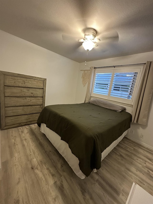 bedroom featuring ceiling fan, wood-type flooring, and a textured ceiling