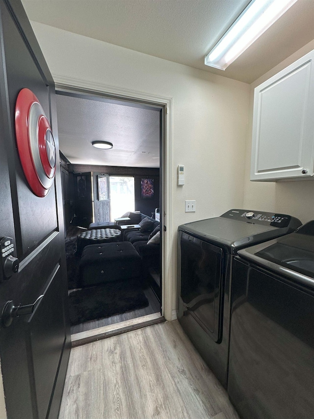 laundry area featuring cabinets, separate washer and dryer, and light hardwood / wood-style flooring