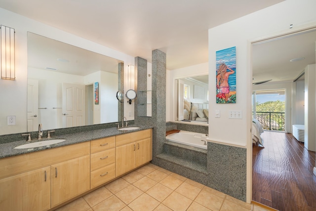 bathroom with tile patterned flooring, tiled tub, and vanity