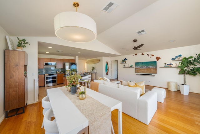 dining room with light hardwood / wood-style flooring, vaulted ceiling, and ceiling fan