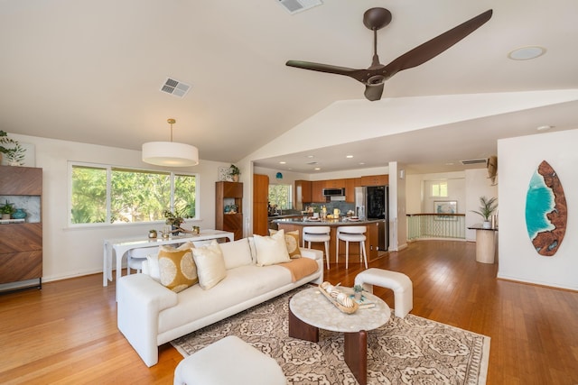 living room with light hardwood / wood-style floors, vaulted ceiling, and ceiling fan