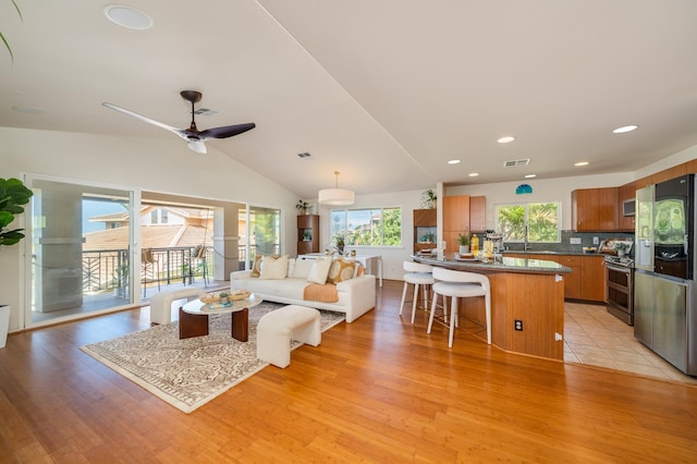 living room featuring light wood-type flooring, ceiling fan, and lofted ceiling