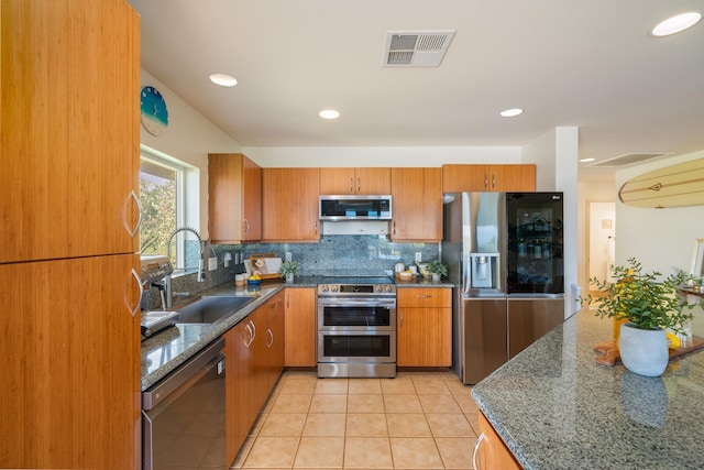 kitchen with sink, dark stone countertops, light tile patterned floors, and appliances with stainless steel finishes