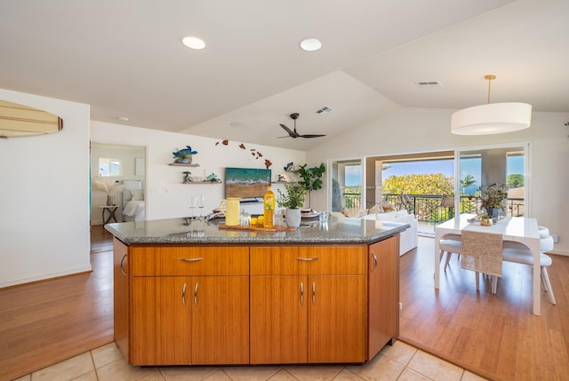 kitchen with vaulted ceiling, dark stone countertops, ceiling fan, and light tile patterned floors