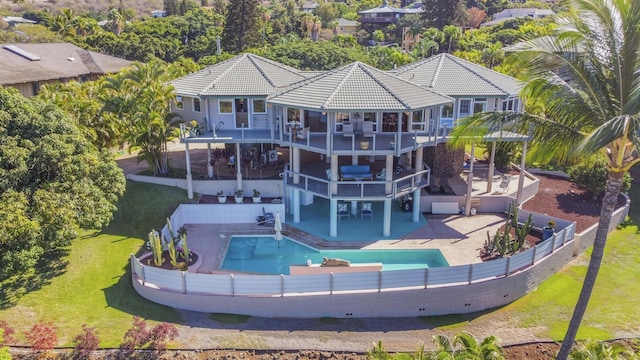 back of property with a patio area, a fenced in pool, a balcony, and a yard