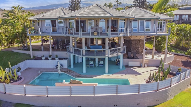 rear view of house featuring a balcony, a fenced in pool, and a patio