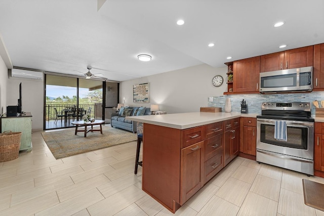 kitchen with a wall of windows, appliances with stainless steel finishes, backsplash, a kitchen bar, and kitchen peninsula