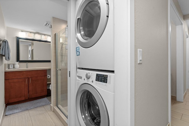 washroom with light tile patterned flooring, stacked washer / drying machine, and sink