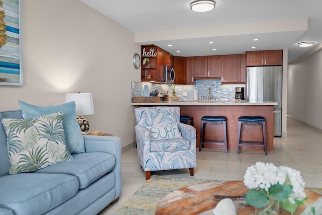 kitchen with sink, appliances with stainless steel finishes, a kitchen bar, decorative backsplash, and kitchen peninsula