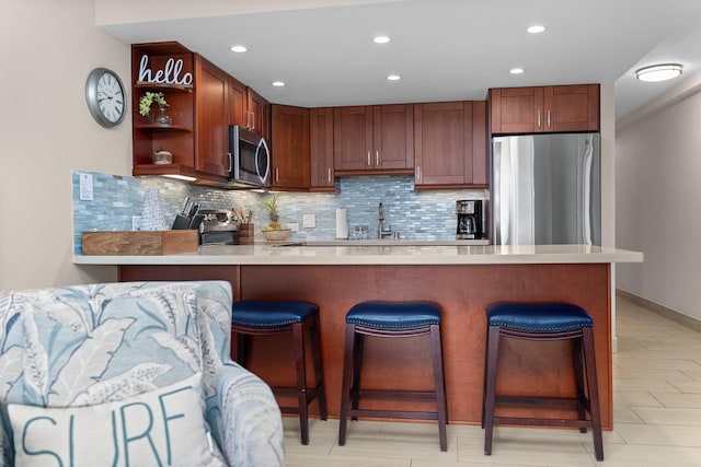 kitchen featuring stainless steel appliances, a breakfast bar area, backsplash, and kitchen peninsula