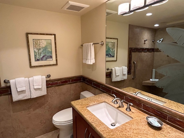 bathroom with tile walls, vanity, toilet, and an enclosed shower