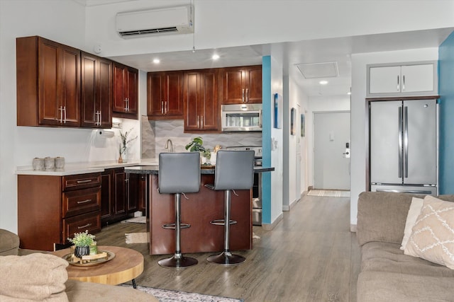 3788 Lower Honoapiilani Rd Unit C102, Lahaina, HI 96761 - kitchen with appliances with stainless steel finishes, a wall unit AC, open floor plan, wood finished floors, and recessed lighting