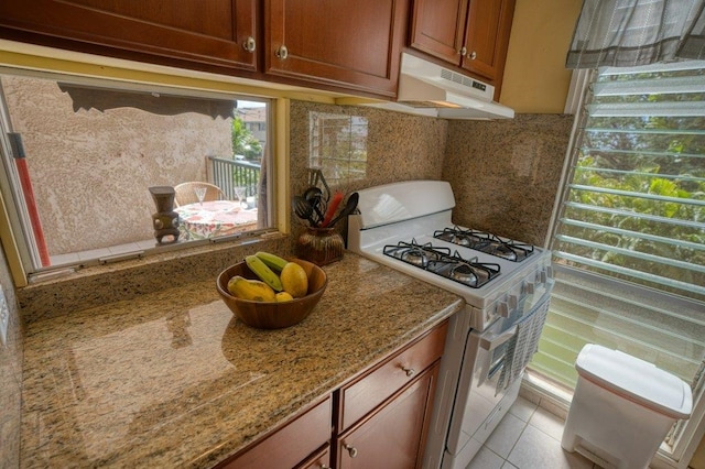 kitchen with light tile patterned flooring, light stone countertops, and white gas stove