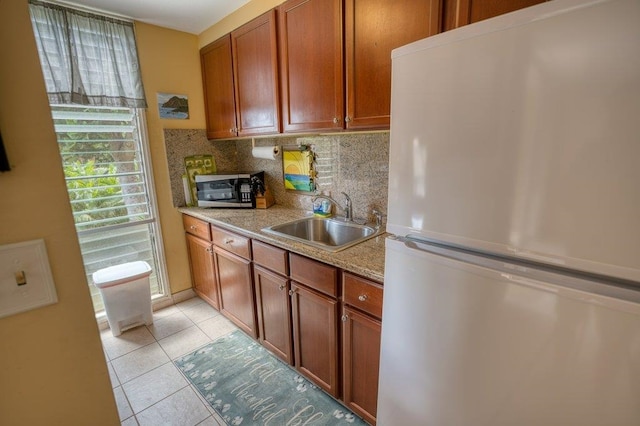 kitchen with appliances with stainless steel finishes, decorative backsplash, light tile patterned flooring, light stone countertops, and sink