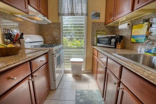 kitchen with light stone counters, sink, light tile patterned floors, tasteful backsplash, and white range with gas cooktop