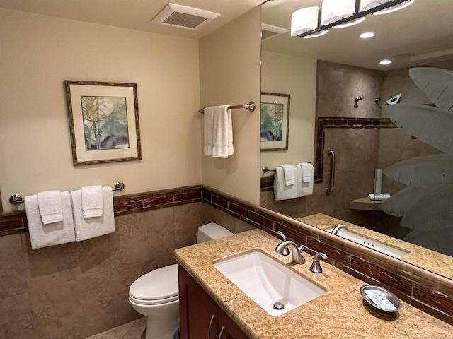 bathroom featuring visible vents, toilet, tile walls, vanity, and tiled shower