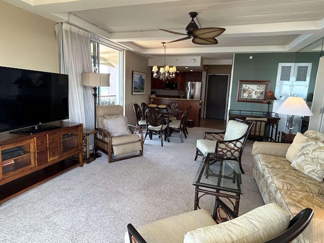 carpeted living room with a tray ceiling and ceiling fan with notable chandelier
