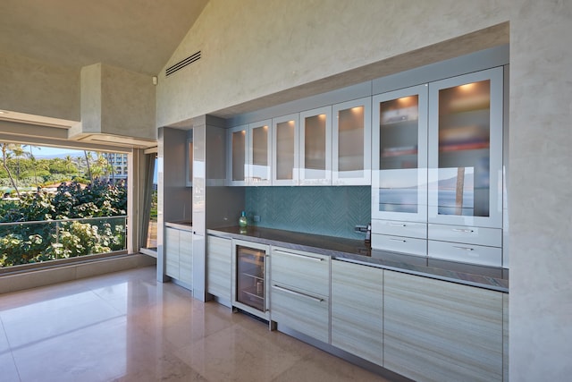 kitchen featuring dark stone counters, beverage cooler, and high vaulted ceiling